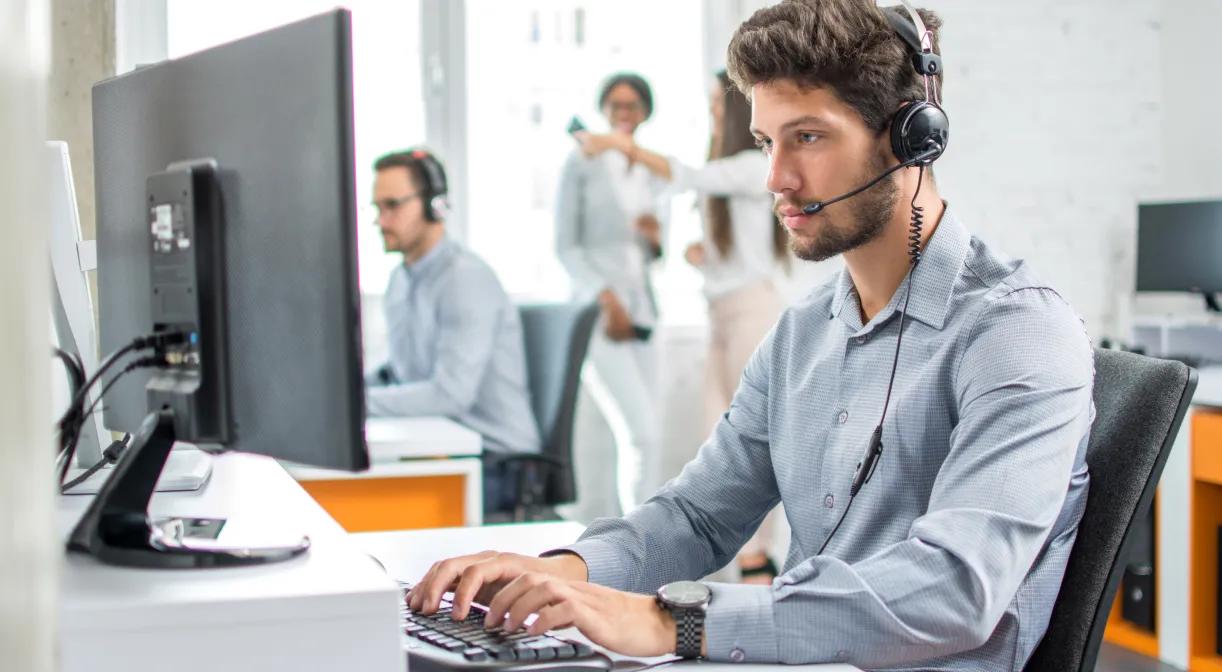 A man in an office wearing a headset, providing IT support for office administration tasks.