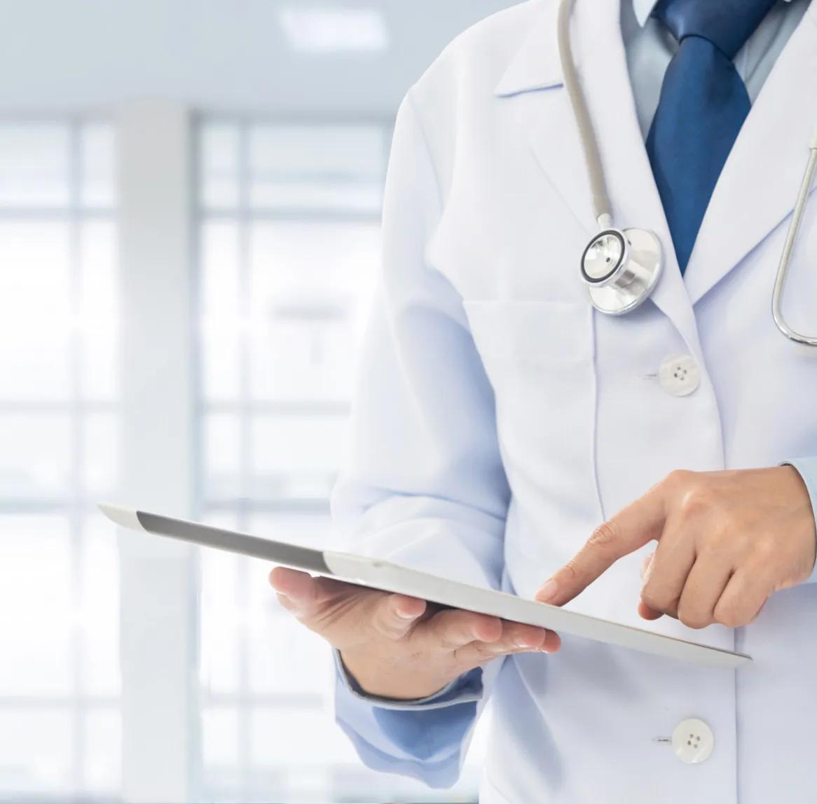 A doctor in a white coat holding a tablet, working on a custom developed software