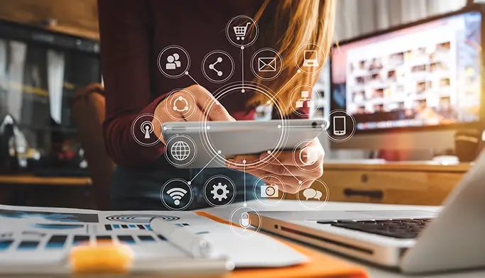 An image of a woman using a tablet displaying icons related to custom software development