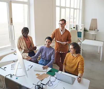 Offshore software development team sitting together with laptops at a table