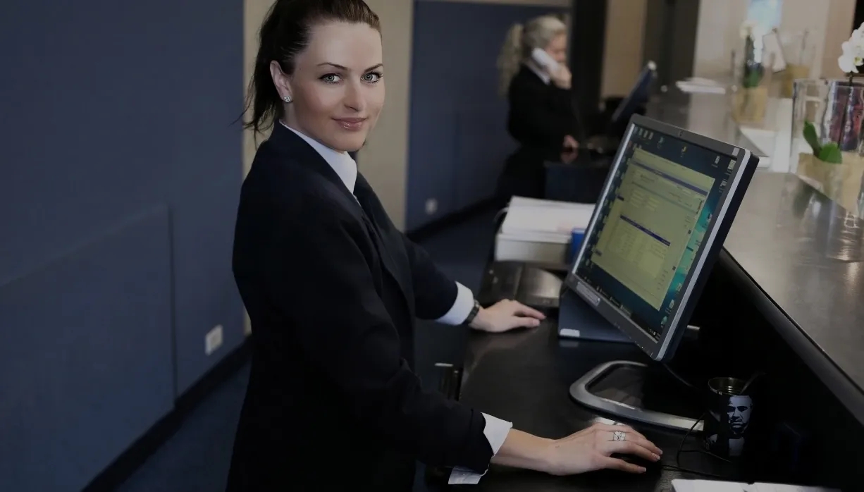 A professional woman in a business suit sits at a desk, working on intelligent reservation management.