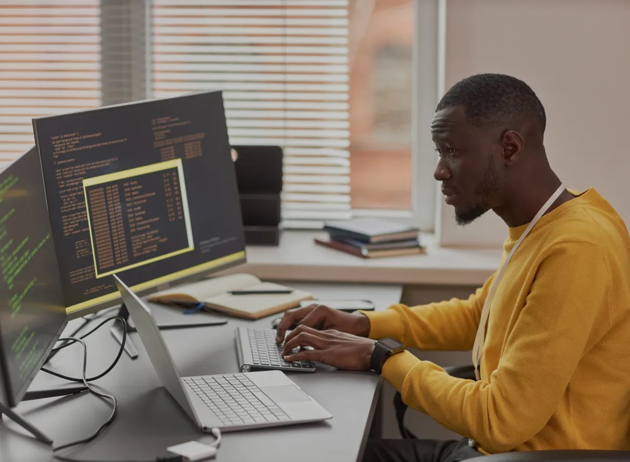 A man in a yellow shirt working on a computer, focusing on cloud management DevOps as a service