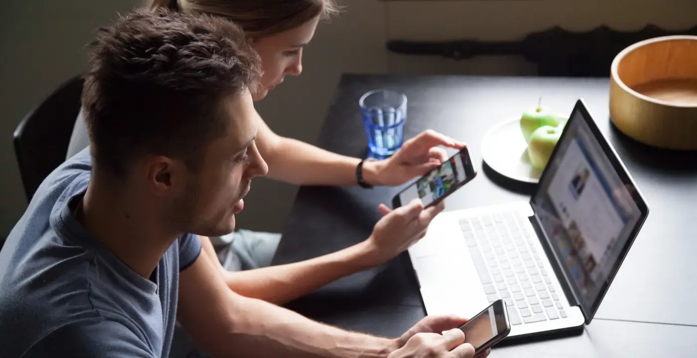 Two individuals engrossed in their devices, accessing real-time information through phones and laptops.