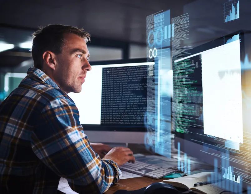 A man focused on a computer screen displaying lines of code.